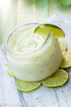 coconut lime salt scrub in a glass jar with limes around it and the words coconut lime salt scrub