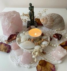 a candle sits on a plate surrounded by sea shells