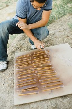 a man sitting on the ground with some sticks in front of him