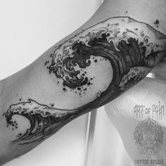 black and white photo of a man's arm with an ocean wave tattoo on it