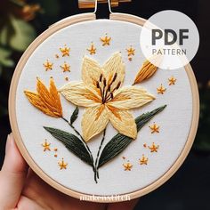 a hand holding up a embroidery kit with yellow flowers on it and stars in the background