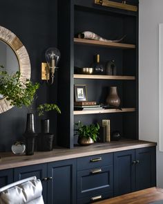 a living room with black walls and wooden shelves filled with books, plants and vases