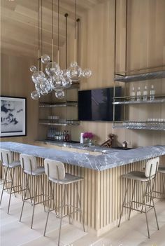 an image of a kitchen with marble counter tops and barstools on the island