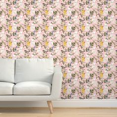 a white couch sitting in front of a wallpapered with pink and purple flowers