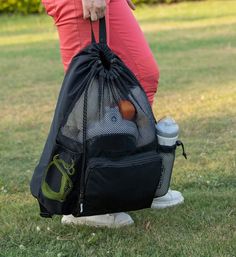 a person holding a black bag with sports equipment in it on top of the grass