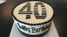 a white and black birthday cake with the number forty on it's top is sitting on a table