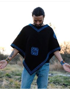 a man wearing a black ponchle with blue designs on his arms and hands