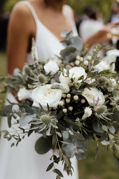 a bouquet of white flowers and greenery on a table