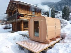 a hot tub sitting on top of a wooden platform next to a snow covered hillside