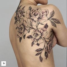 a woman's back with flowers and leaves on her left shoulder, which is covered in black ink