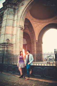 a man and woman standing in front of an arch