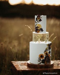 a three tiered wedding cake with sunflowers on it