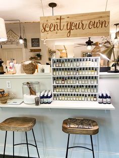 two stools in front of a counter with bottles on it and a sign that says, scent your own