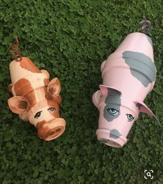 two toy cows laying in the grass with their heads turned to look like they are looking at something