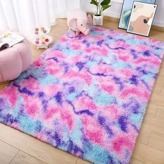 a pink and blue area rug on the floor next to a stuffed animal in front of a window