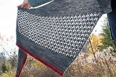 a woman is holding up a crocheted shawl in the grass with her hands