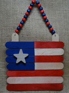 an american flag made out of popsicle sticks and beaded necklace on a canvas background