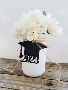 a mason jar filled with white flowers and a graduation cap