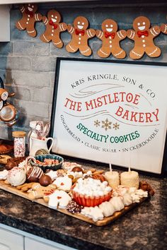 some cookies and cupcakes are on a counter with a sign that says the mistlet of bakery