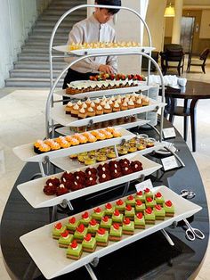 a man standing next to a table filled with cakes and desserts on trays