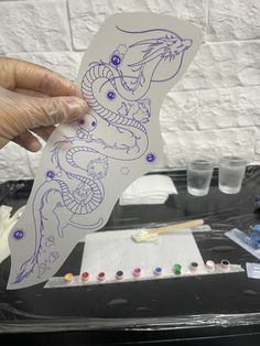 a person holding up a piece of paper with an image of a dragon on it