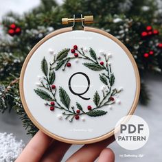 a hand embroidered christmas wreath with the letter q on it