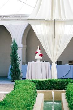 a wedding cake sits on top of a table in the middle of an outdoor garden