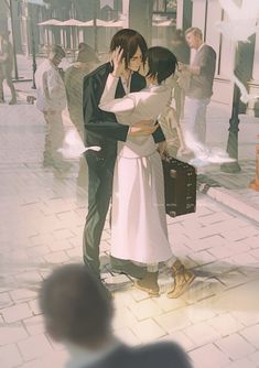 a man and woman kissing on the street with people in the back ground behind them