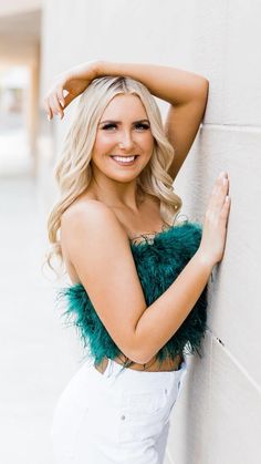 a beautiful blonde woman leaning against a wall