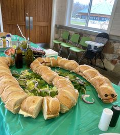 a table topped with sandwiches and salads on top of green tables clothed in blue