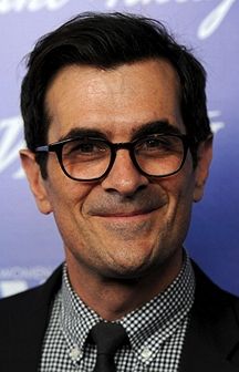 a man wearing glasses and a suit smiling