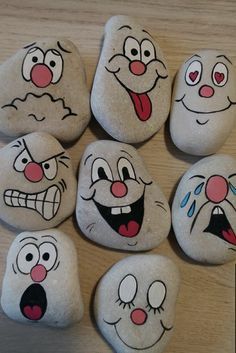 some rocks with faces painted on them sitting on a wooden table next to each other