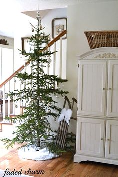 a small christmas tree sitting in the corner of a room next to a white cabinet