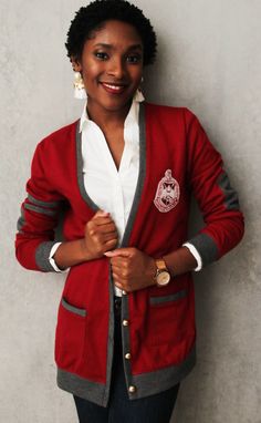 a woman standing in front of a wall wearing a red jacket