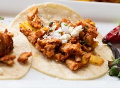 two tortillas with meat and cheese on them sitting on a plate next to peppers