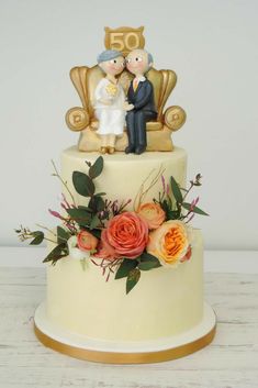 a wedding cake decorated with flowers and figurines