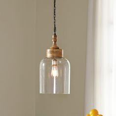 a glass light hanging over a table next to a vase with yellow flowers on it