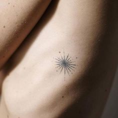 the back of a woman's stomach with a small starburst tattoo on it