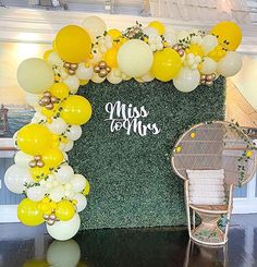 a chair sitting under a yellow and white balloon arch