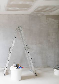 a white bucket and some paintbrushes in a room