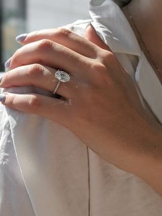 a woman's hand with a diamond ring on her left wrist, wearing a white shirt