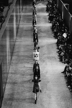 a black and white photo of people walking down the runway in front of an audience