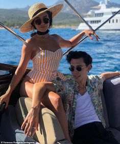 a woman sitting on the back of a boat next to a man in a hat