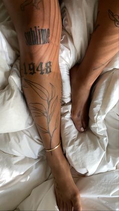 a person laying in bed with tattoos on their legs