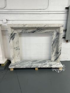 a marble fireplace surround in a room with white walls and grey flooring on the ground