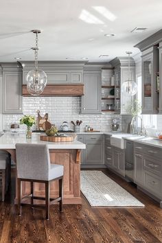 a large kitchen with gray cabinets and wooden flooring, along with a breakfast nook