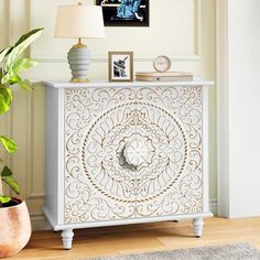 a white cabinet sitting next to a potted plant