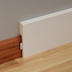 the corner of a room with wood flooring and white paint on the wall behind it