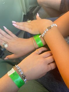 three girls wearing bracelets and rings on their hands in the back seat of a car