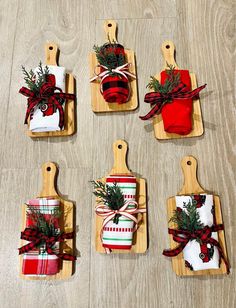 six small wooden cutting boards with wrapped christmas gifts on them, tied in red and green bows